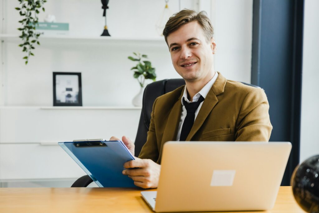 Business portrait - businessman sitting in in office working with laptop computer.