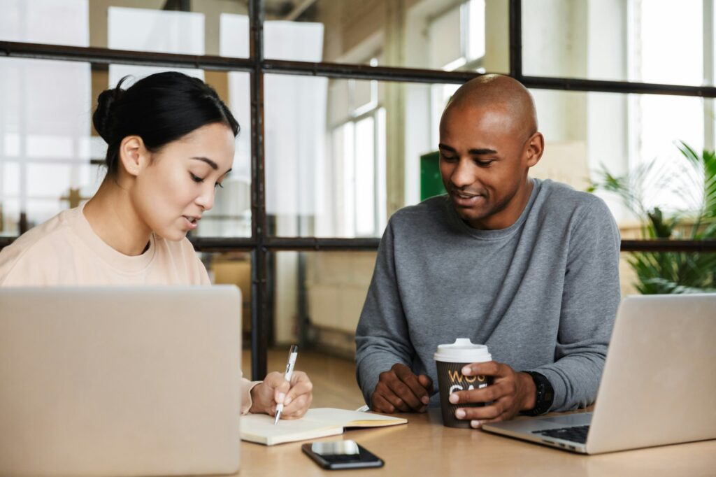 Image of multiethnic young coworkers working on laptops in office